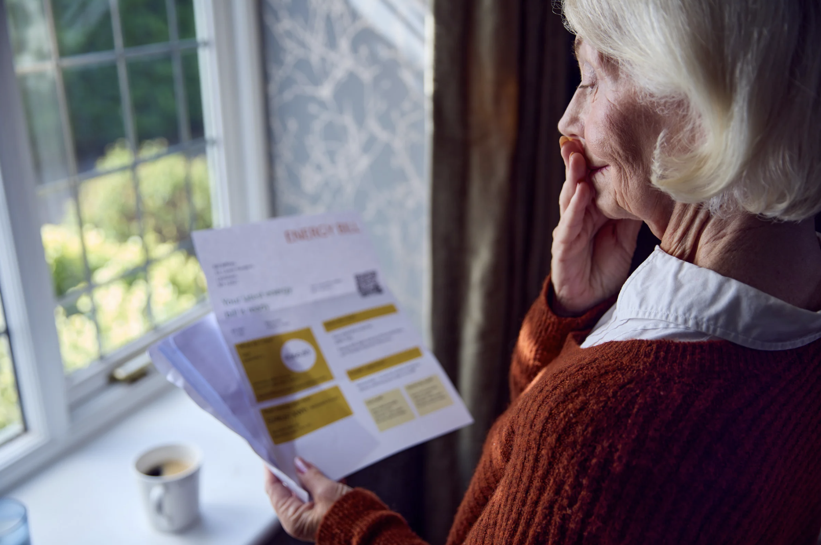 Photo of older woman looking at a high utility bill meant to symbolize Indiana ratepayers who are now facing massive increases from utilities like Duke, CenterPoint and NIPSCO